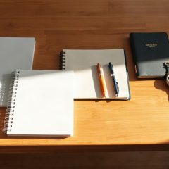 Cahiers a spirale, agenda et stylos poses sur une table en bois